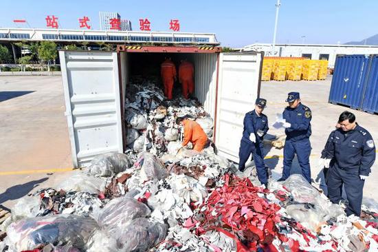 2017年12月21日，厦门海关工作人员在海沧查验场查验走私的进口牛皮革洋垃圾。（新华社）